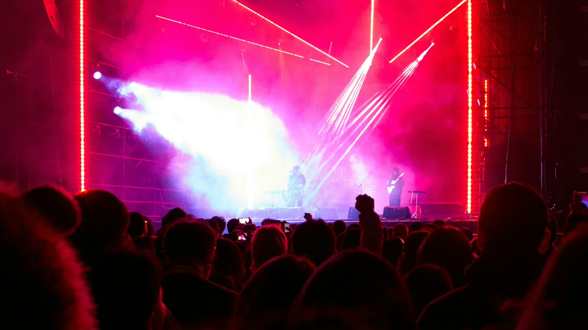 Crowd in front of a lit concert stage